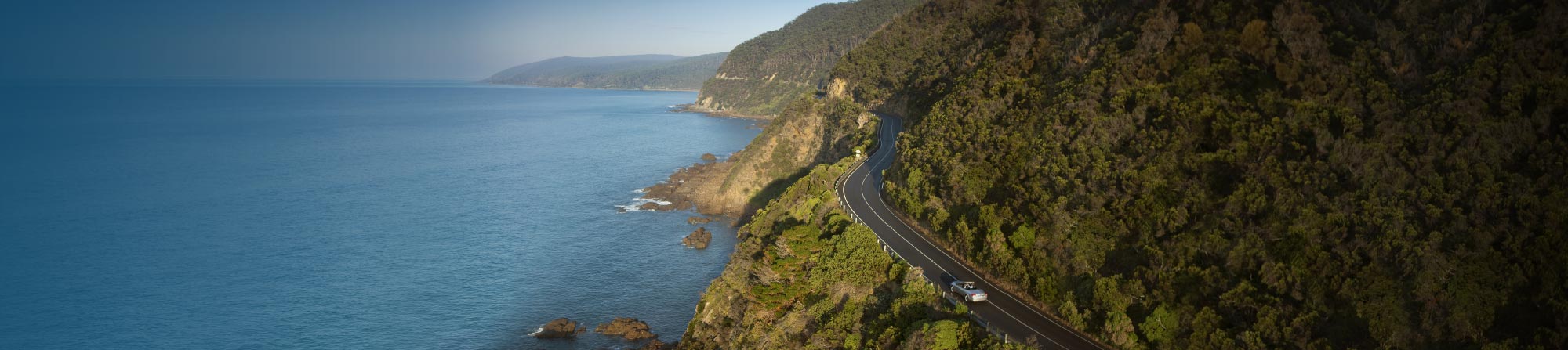 Aerial view of the great ocean road winding along, cut into the side of cliffs that drop into the sea